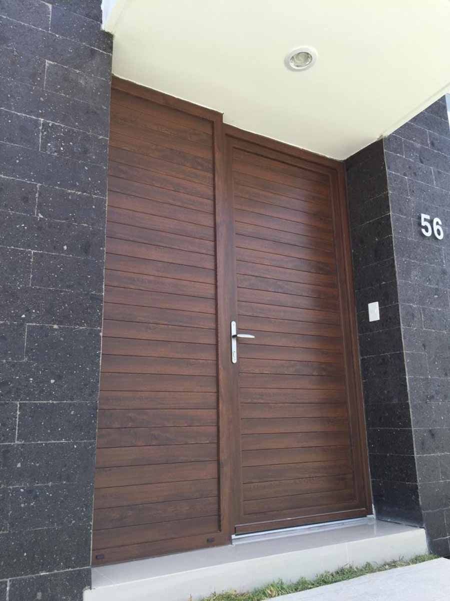 A large wooden door is sitting in front of a black brick wall.