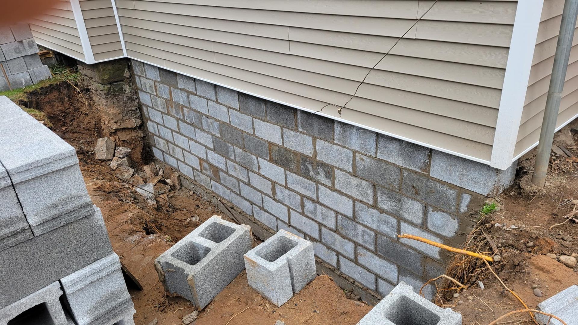 A long, light blue painted brick house with a white trim roof, a side entrance, and a green lawn under a partly cloudy sky.