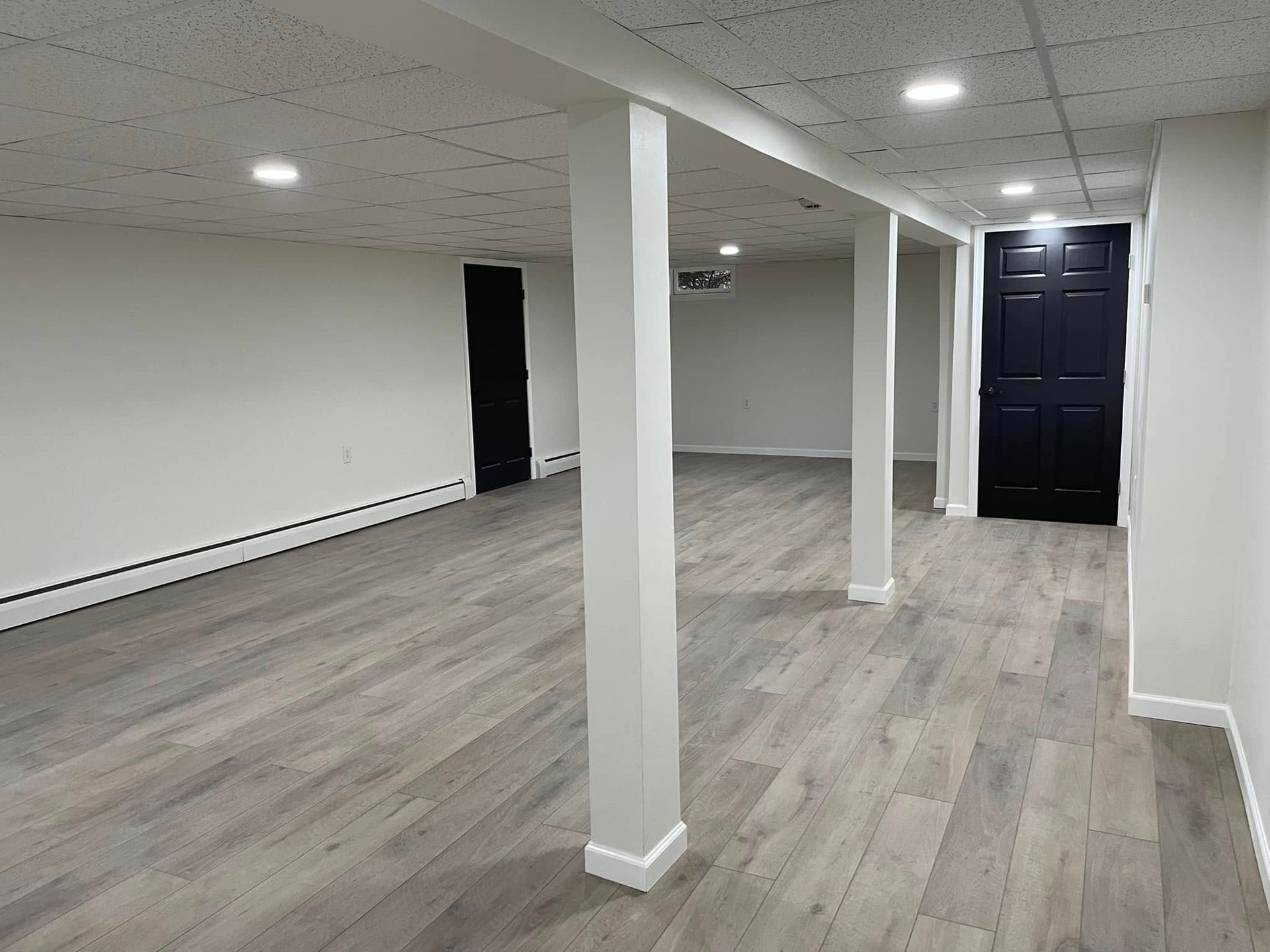 A modern kitchen with white cabinets, speckled granite countertops, stainless steel appliances, and wood-look flooring.