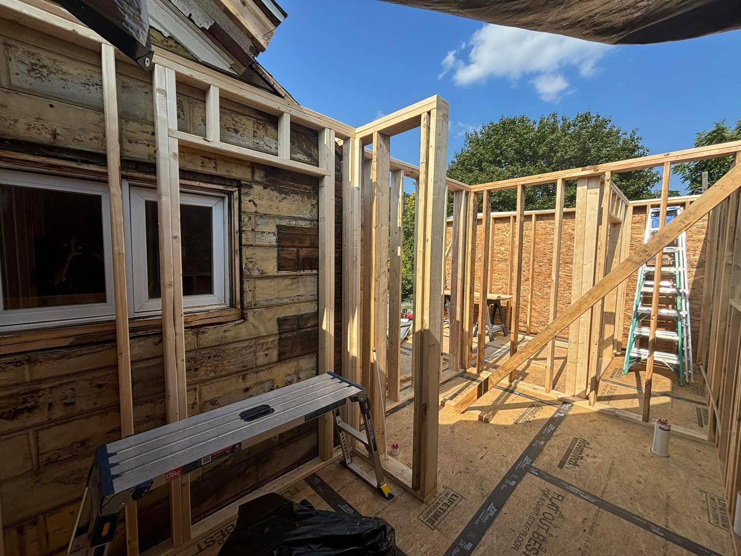 A room featuring light-colored, square-patterned vinyl flooring next to wood-toned planks, with a white cabinet in the back.