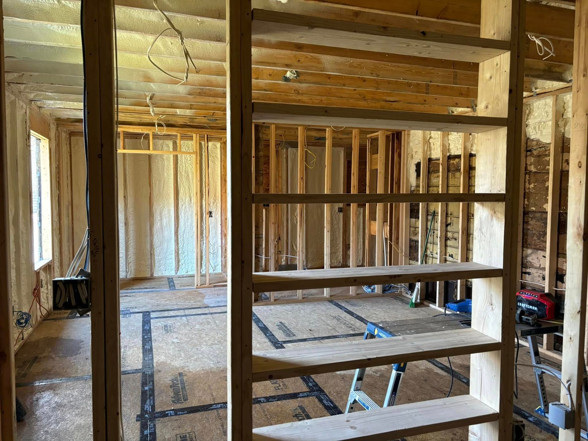 Interior view of a residential construction project showing wood framing, open wall studs, and installed shelf supports.