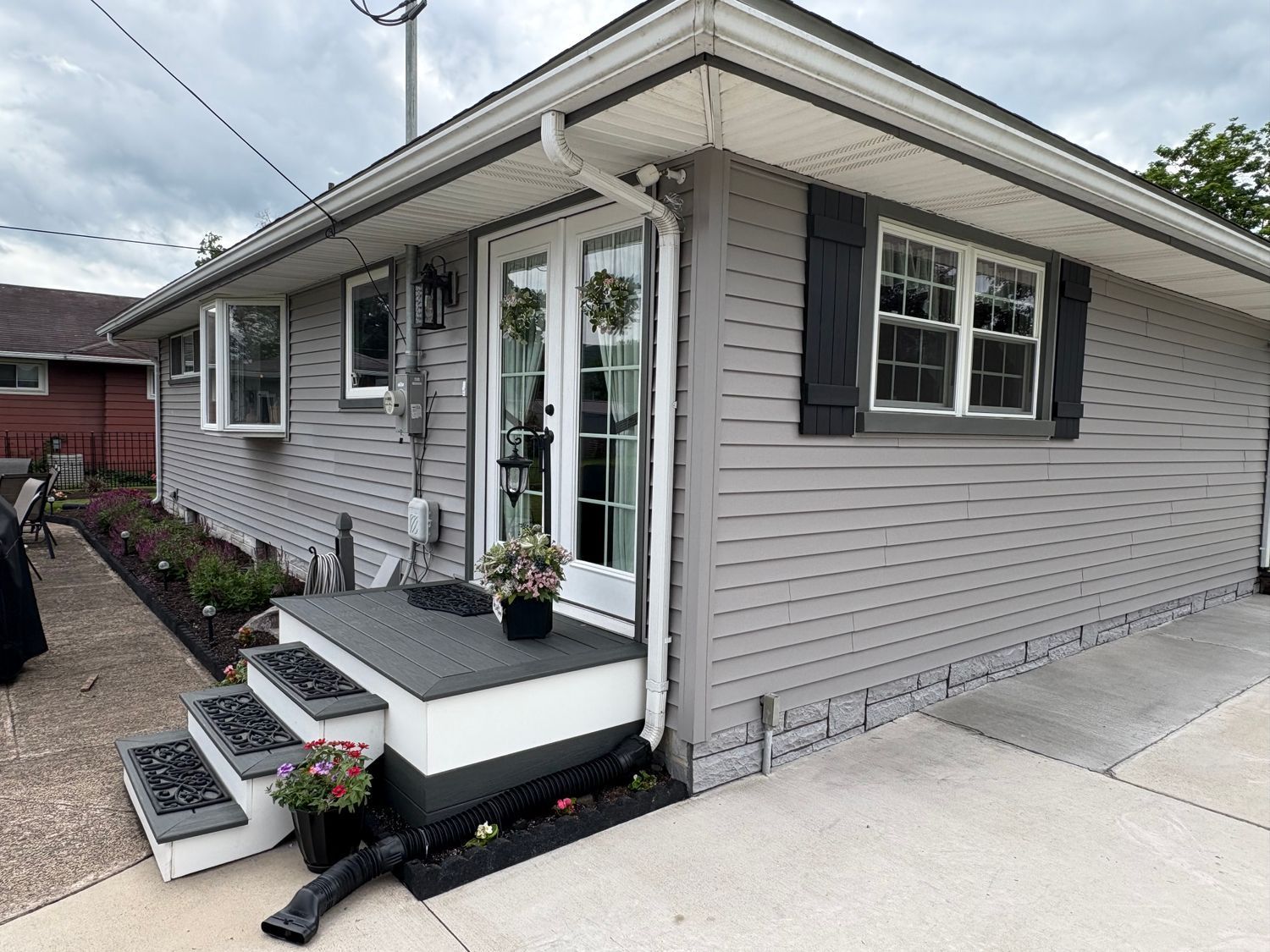 Exterior view of a light-colored, horizontal-sided gable roof section of a building under a gray, overcast sky.