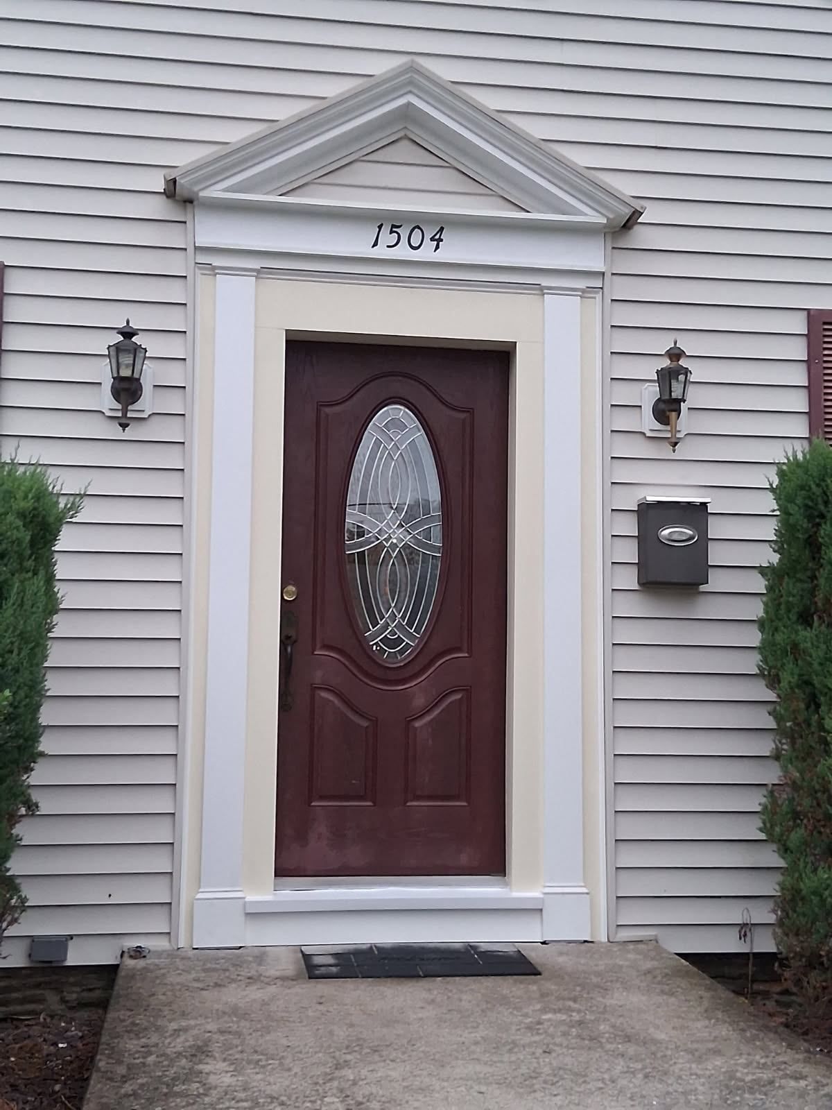 A wood-framed screen door leading from a tiled, covered porch to a yard with a white pickup truck in the background.