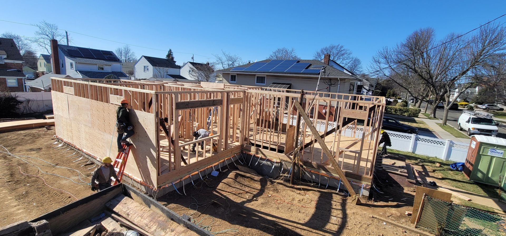 Workers frame the walls of a residential house construction project on a sunny day.