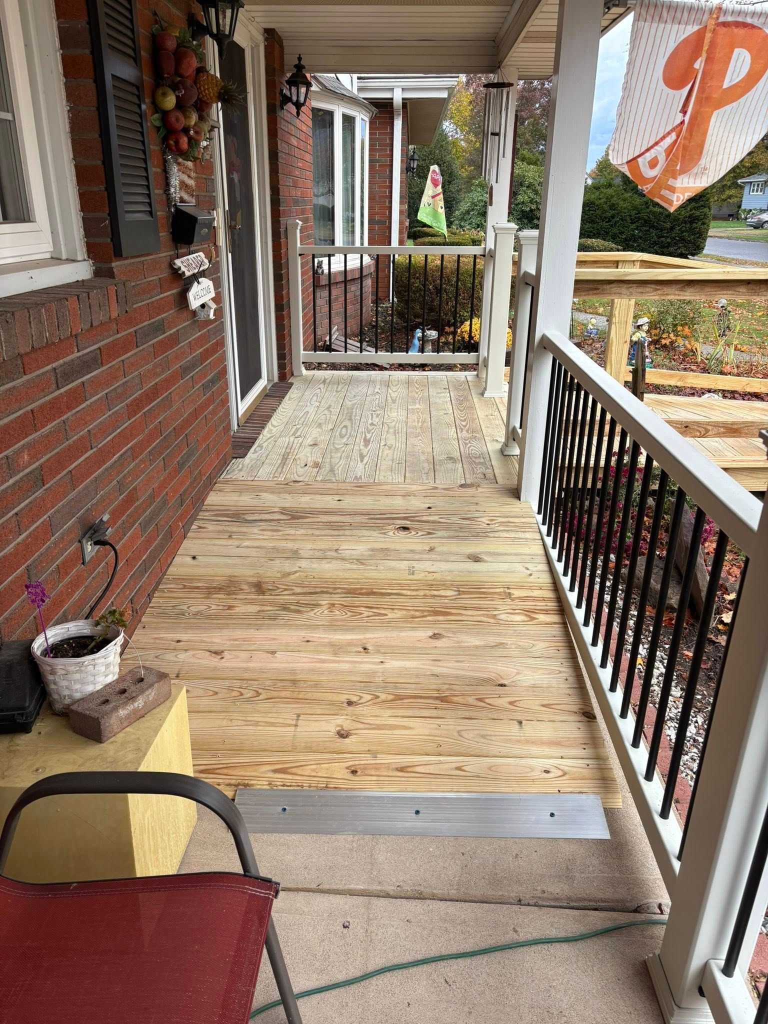A new plywood ramp installed over an existing front porch, leading to the entrance of a brick house.