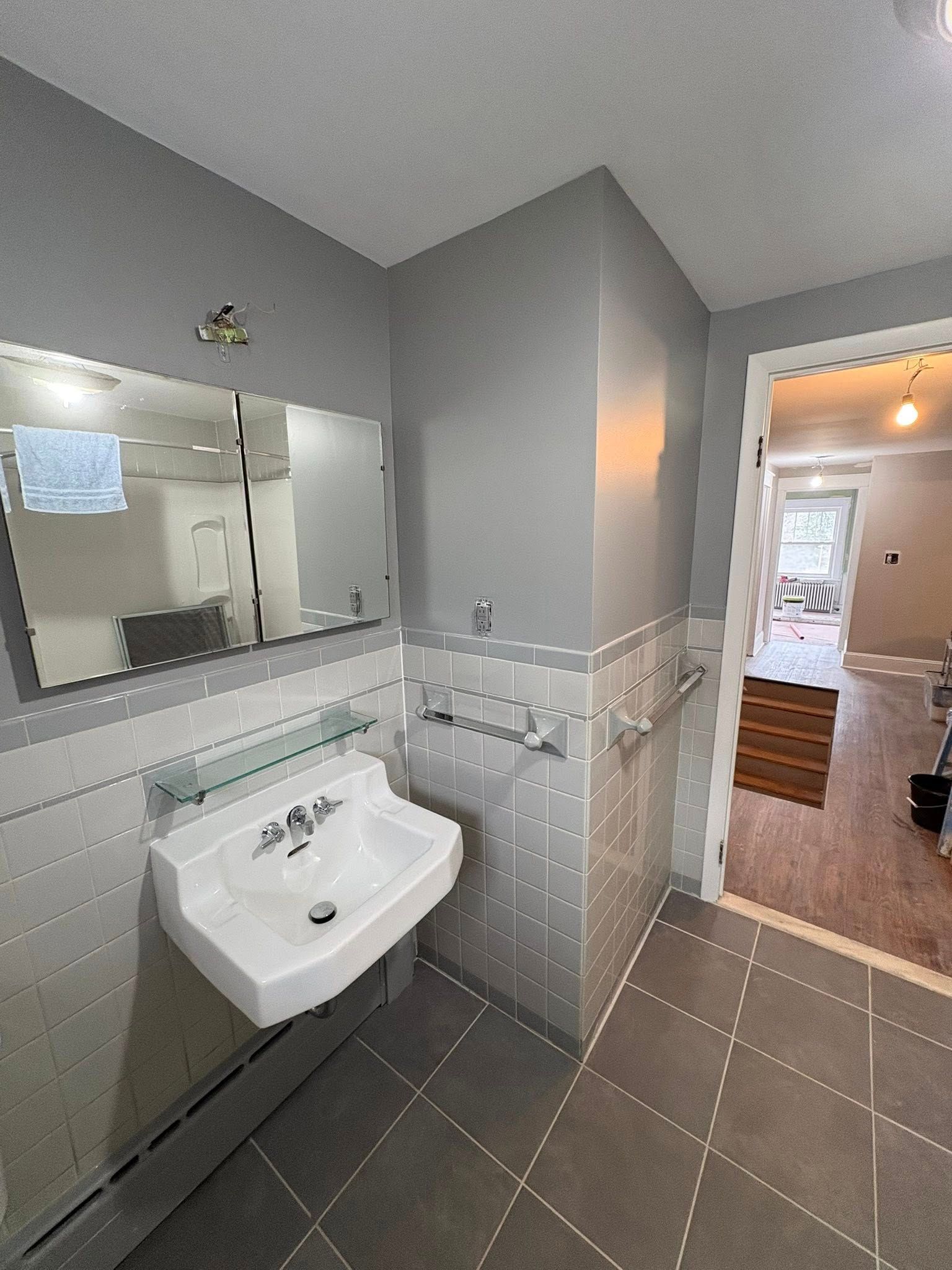 A white bathtub and shower surround with a black faucet, handle, and drain in a bathroom.