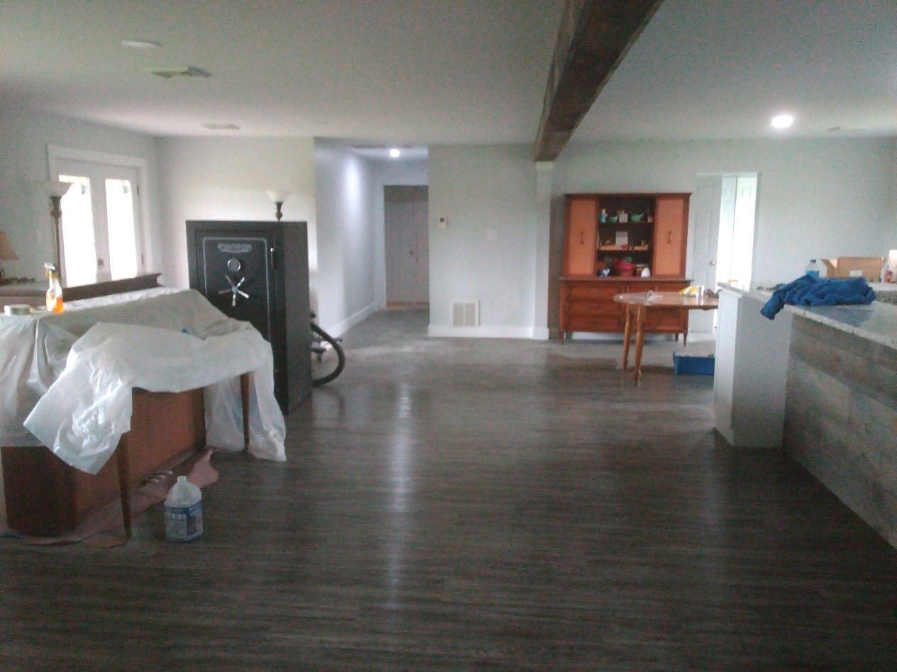An open-concept living area with dark wood flooring, a covered piece of furniture, a large black safe, and a wood hutch.