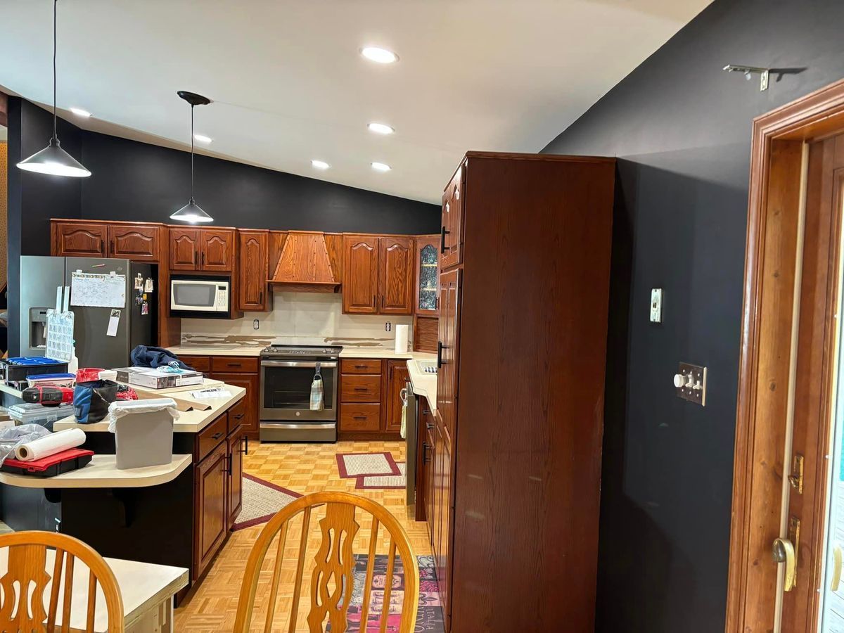 A kitchen with dark walls, wooden cabinets, stainless steel appliances, a center island, and tiled flooring.