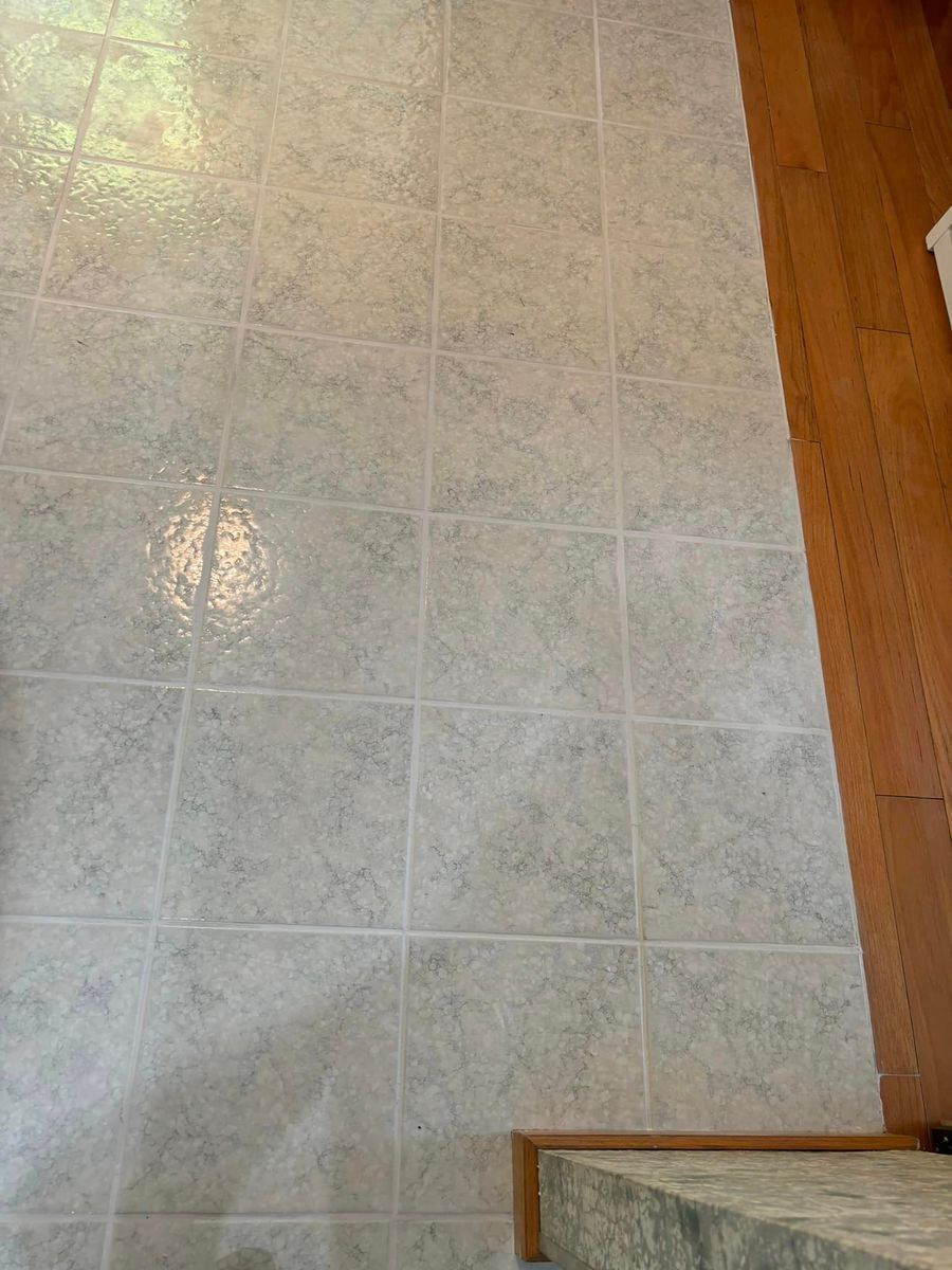 A top-down view of light-colored, square vinyl floor tiles bordered by warm-toned wooden trim.