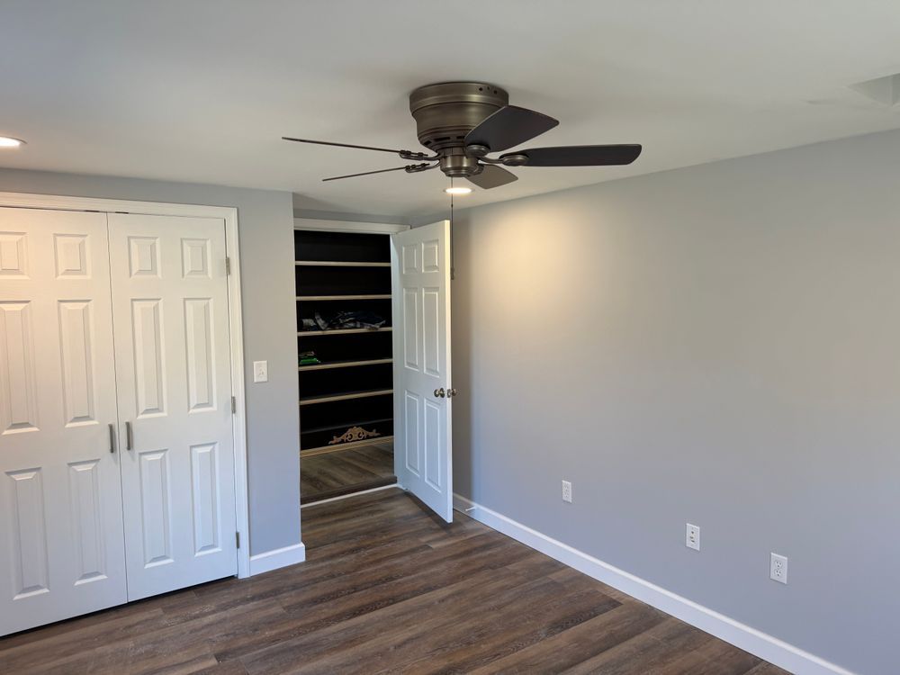 A person works in a room undergoing renovation with exposed wooden door frames, tools, and construction supplies.