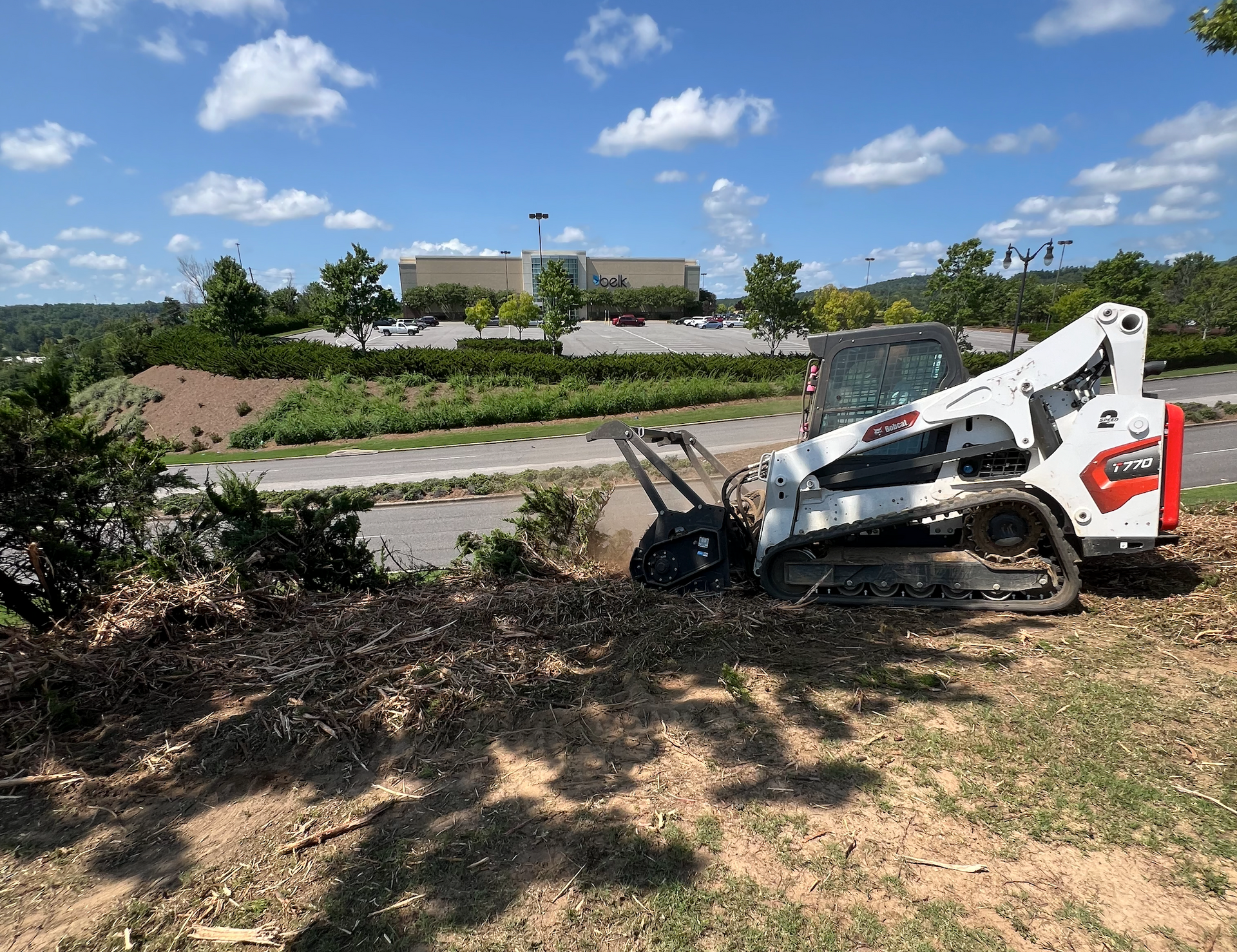 Freshly poured concrete driveway with a worker, surrounded by trees and a house.