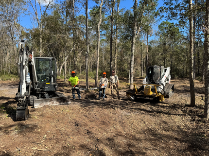 Stone retaining wall with a graded hillside and a house in the background.