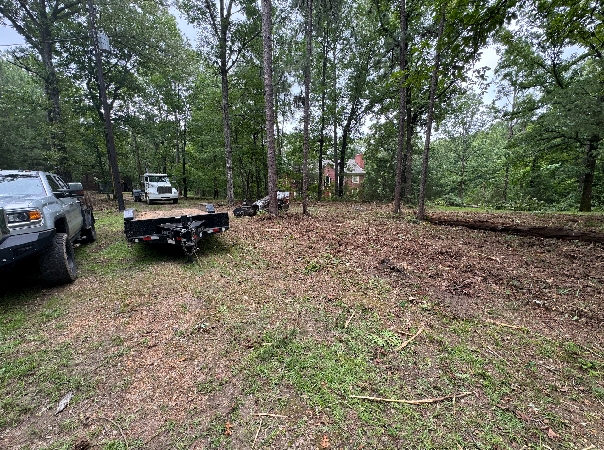 Freshly poured concrete driveway with a worker, surrounded by trees and a house.