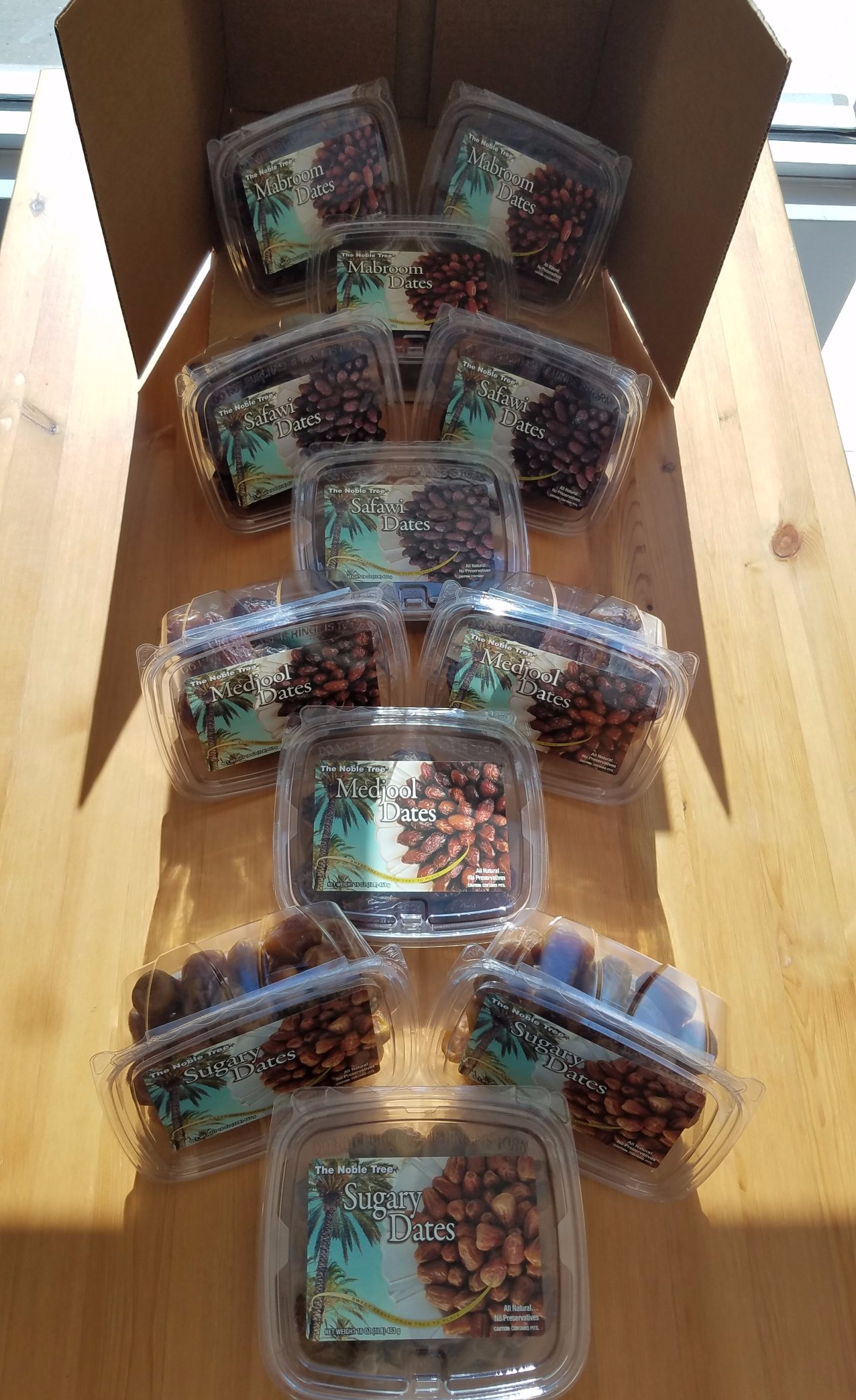 A box filled with plastic containers of food is sitting on a wooden table.