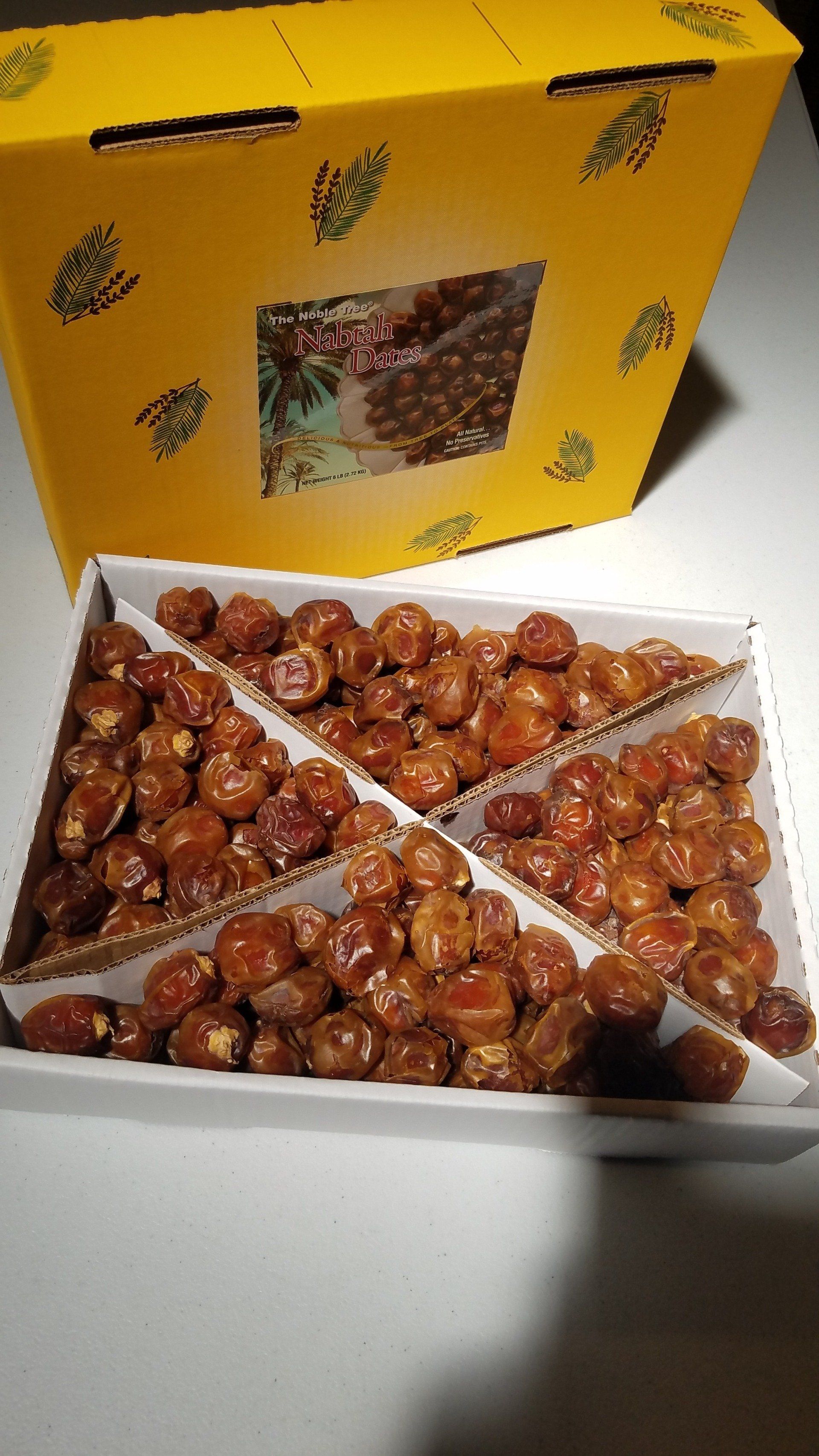 A box of dates is sitting on a table next to a yellow box.