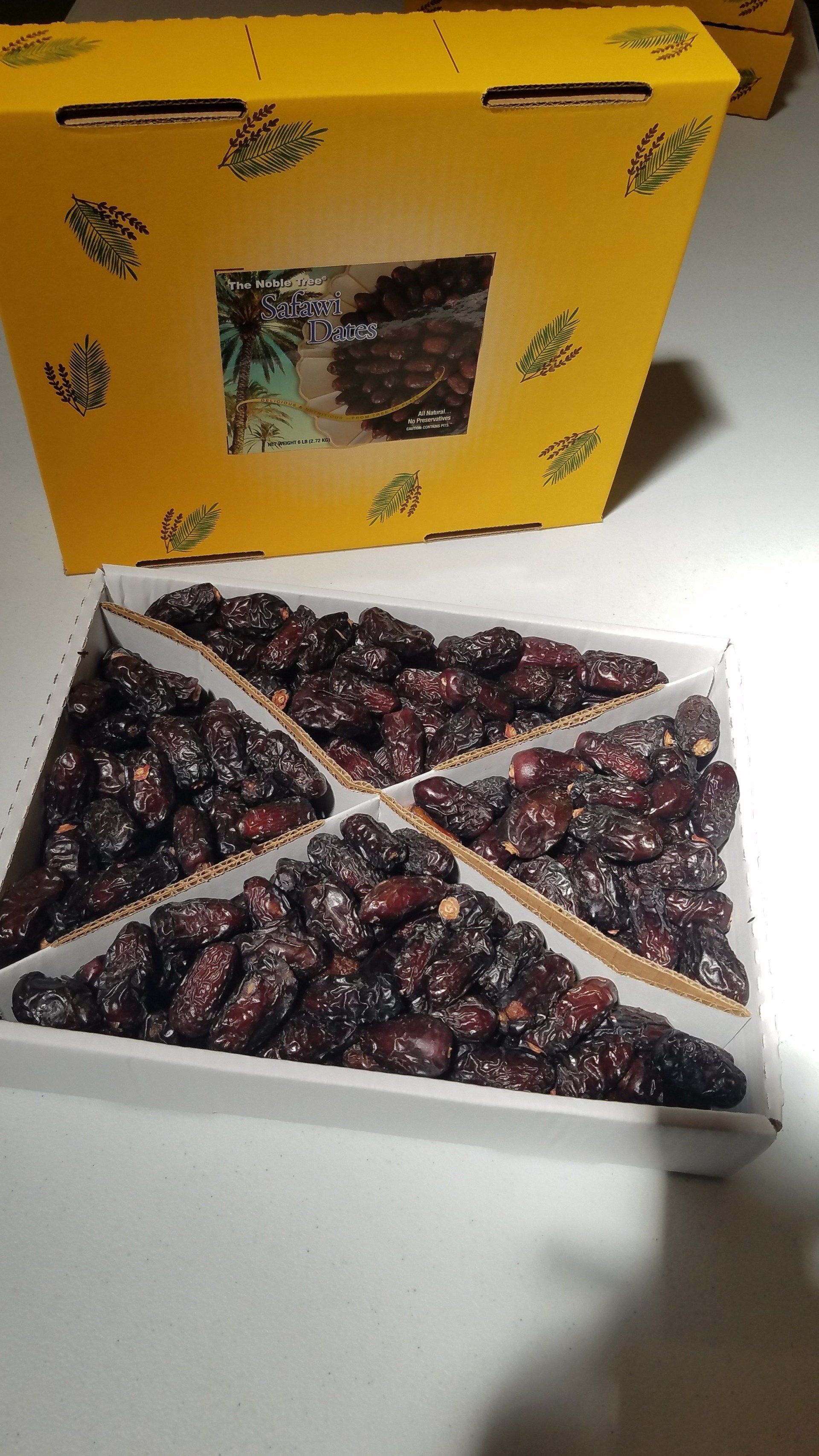 A box of dates is sitting on a table next to a yellow box.
