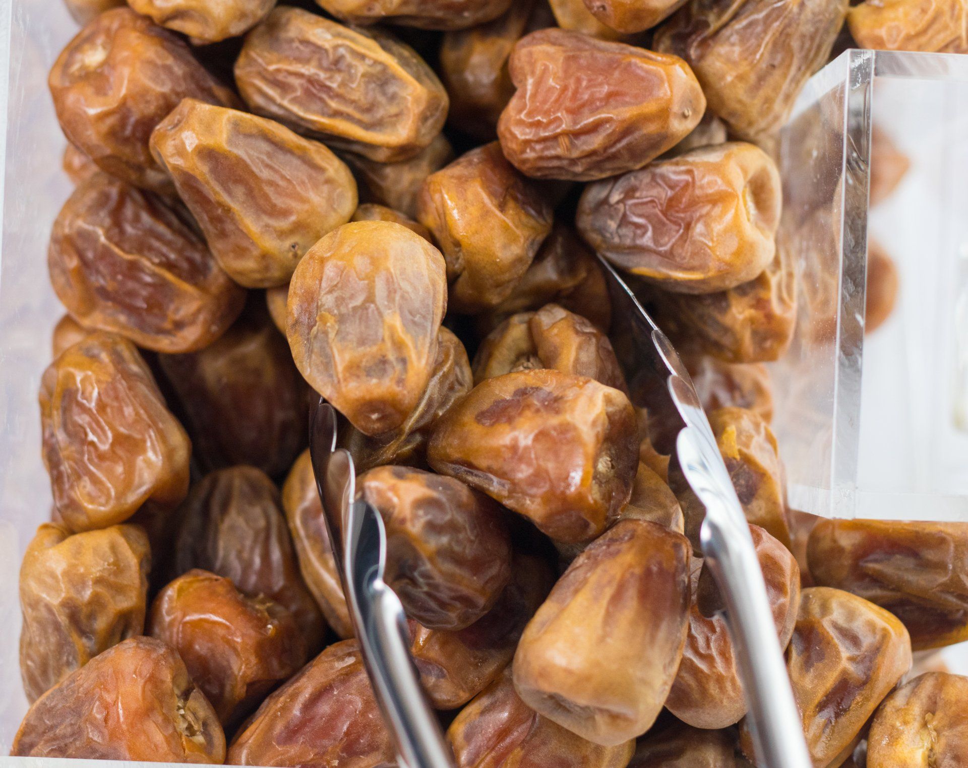 A pile of dates with tongs on top of them.