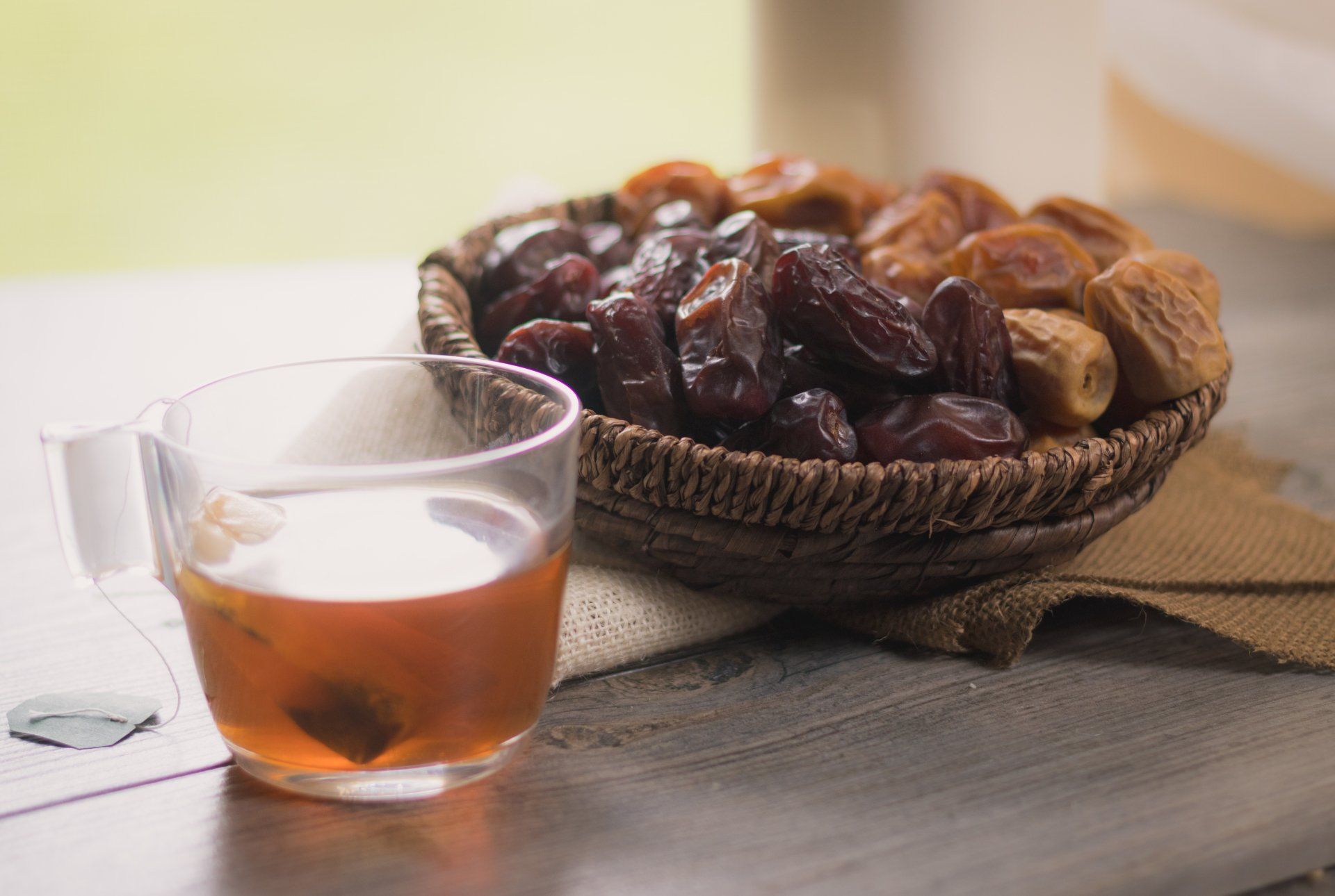 A basket of dates and a glass of tea on a table.