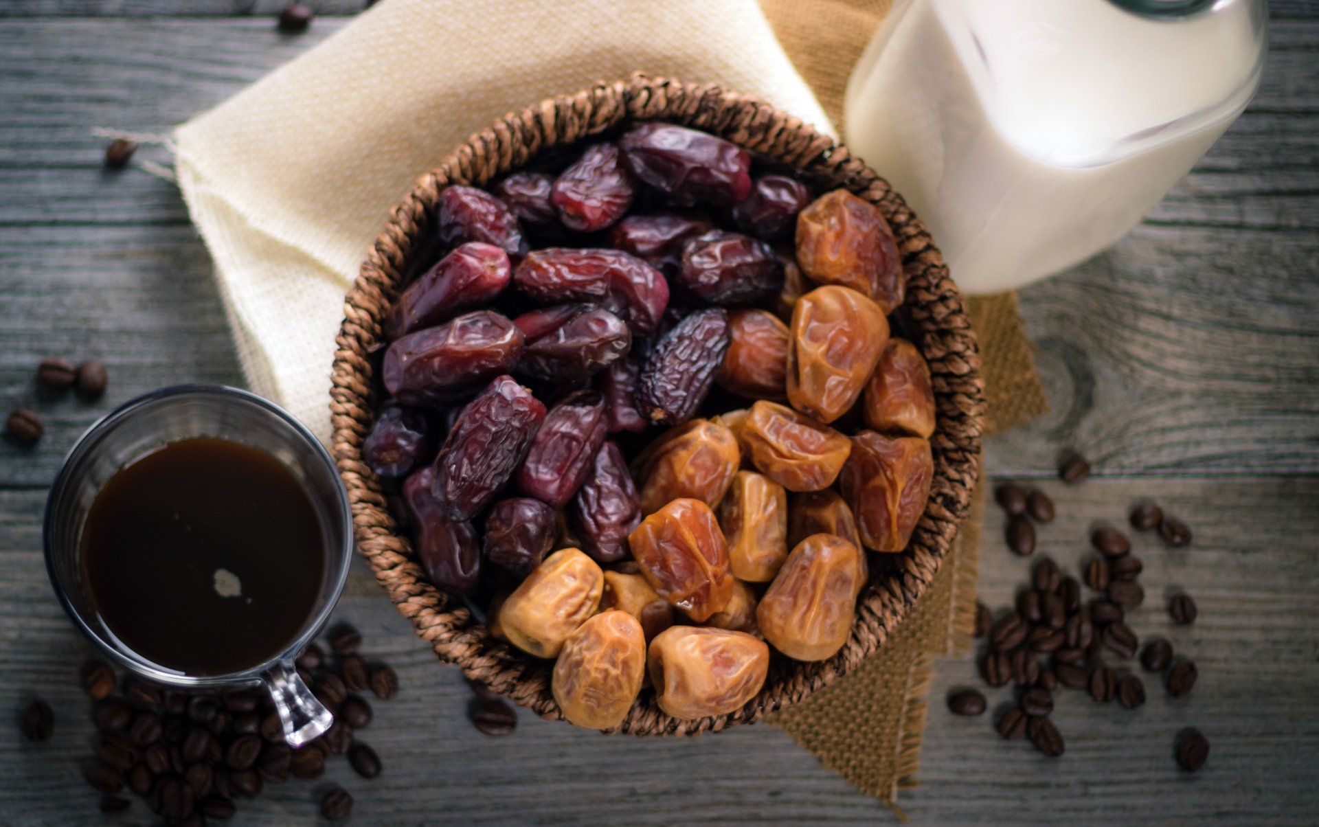A bowl of dates and a cup of coffee on a wooden table.