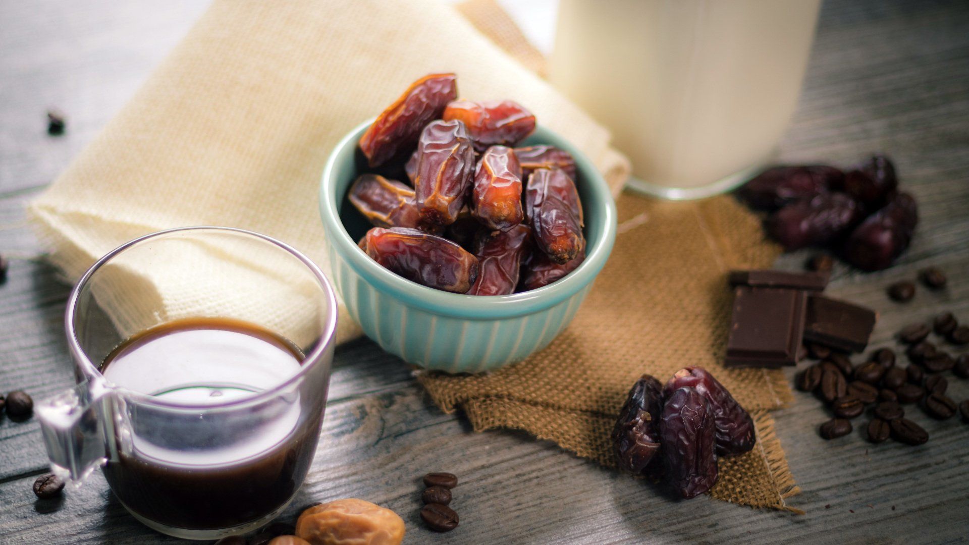 There is a bowl of dates and a cup of coffee on the table.