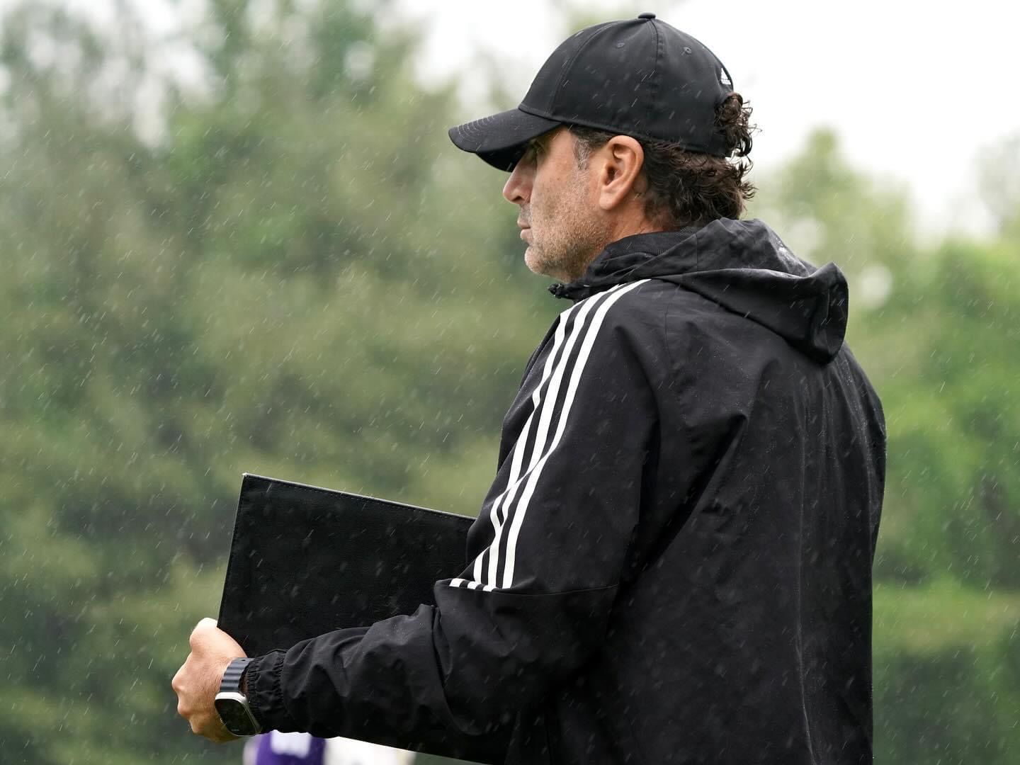 A headshot of someone called Lewis Neal. He is standing against a purple wall
