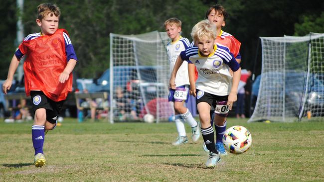 Two boys chasing a soccer ball during practice 