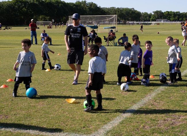 A coach surrounded by young players warming up on the field