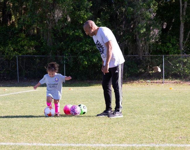 A soccer coach instruction a player on how to kick a ball