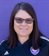 A headshot of someone called Lewis Neal. He is standing against a purple wall