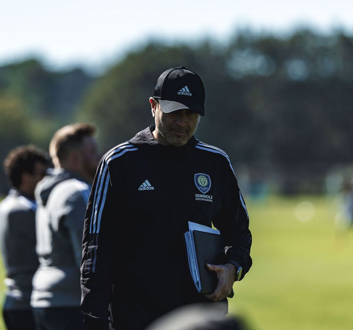 A soccer coach holding a clipboard walking