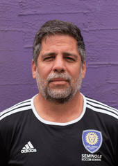 A headshot of someone called William Diaz. He is standing against a purple wall