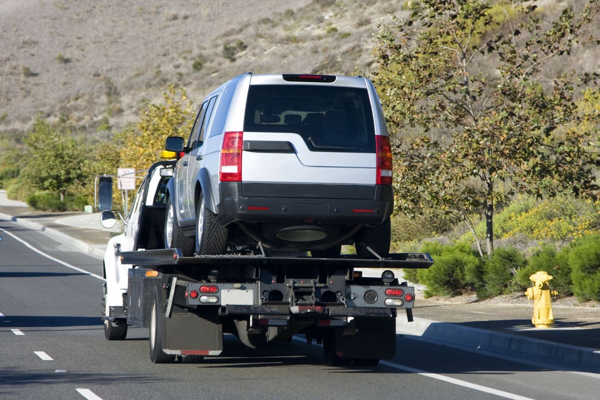 A tow truck is towing a suv down the road.