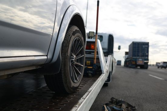A car is being towed by a tow truck on a highway.