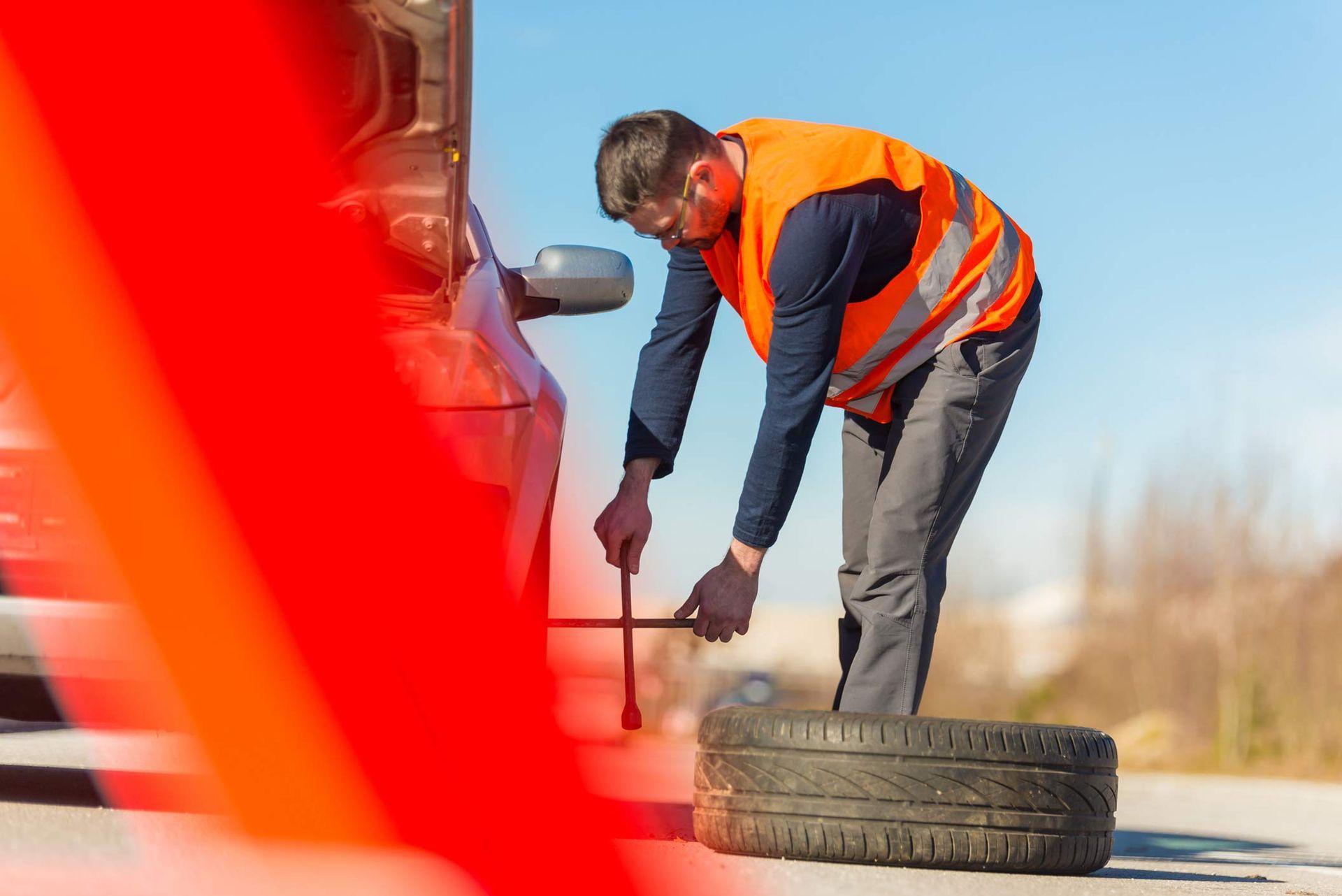 A man is changing a tire on the side of the road.