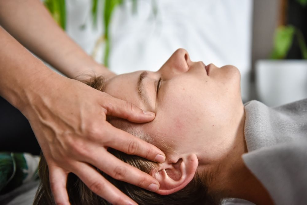 A Woman Is Getting A Head Massage From A Person — Hands on Healing Massage In Tamworth, NSW