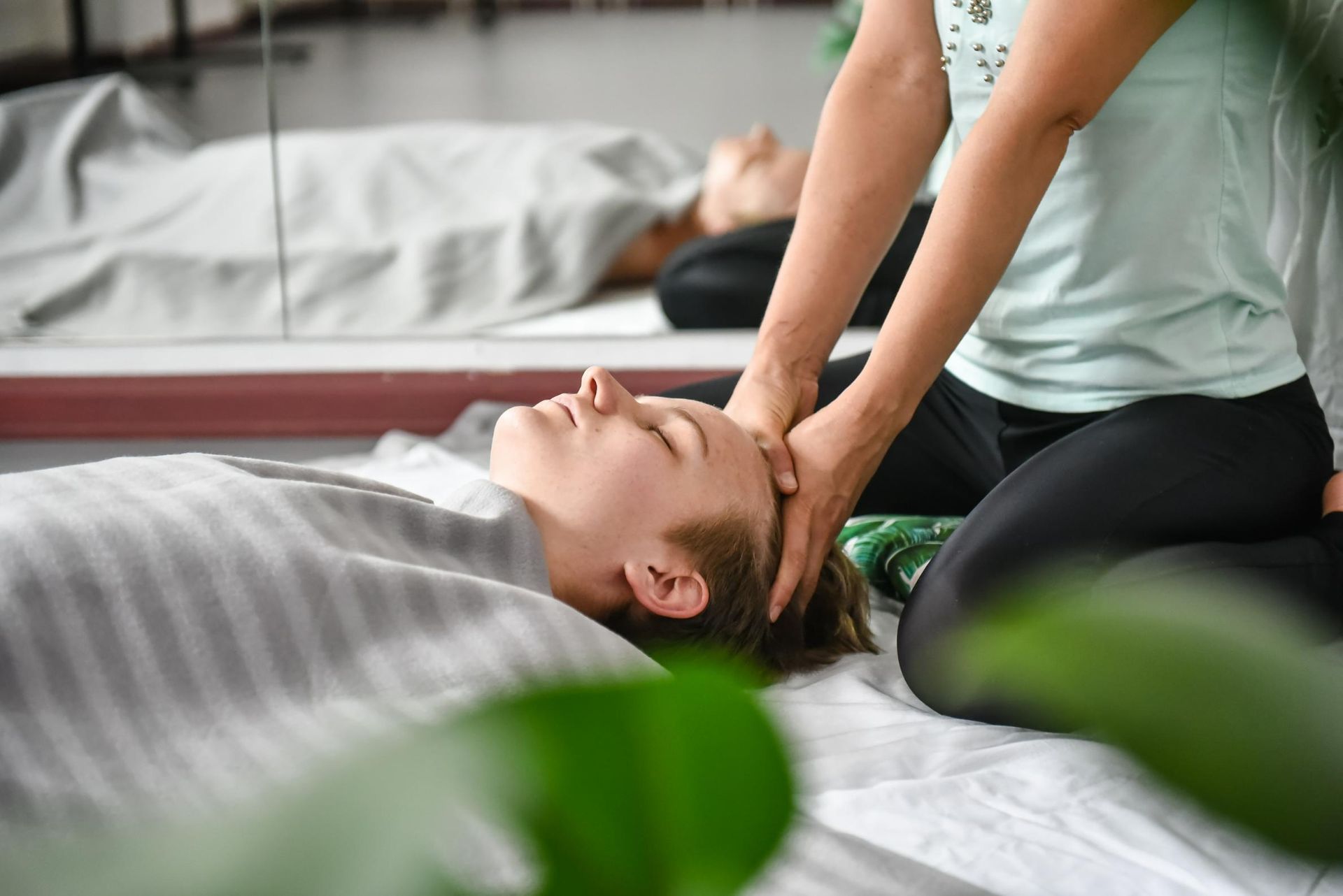 A Woman Is Getting A Massage On Her Head While Laying On A Bed — Hands on Healing Massage In Tamworth, NSW