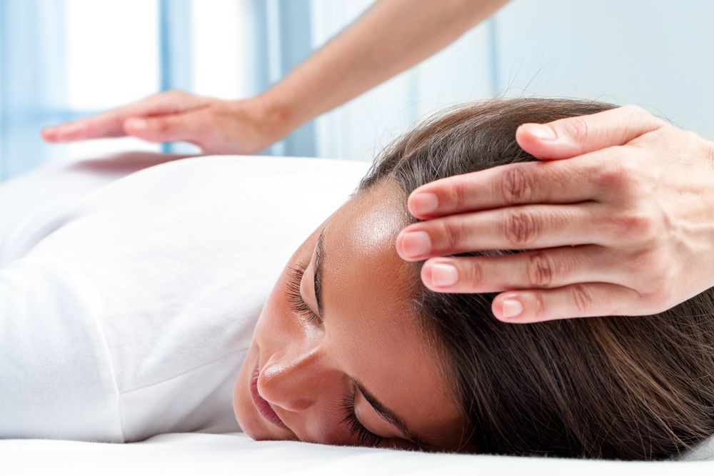 A Woman Is Getting A Reiki Treatment On Her Head — Hands on Healing Massage In Tamworth, NSW