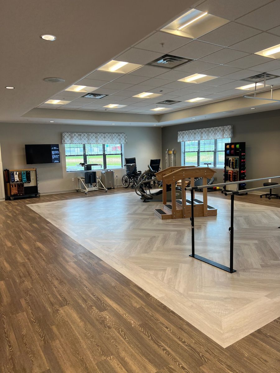 A physical therapy room with exercise equipment and light-colored flooring.