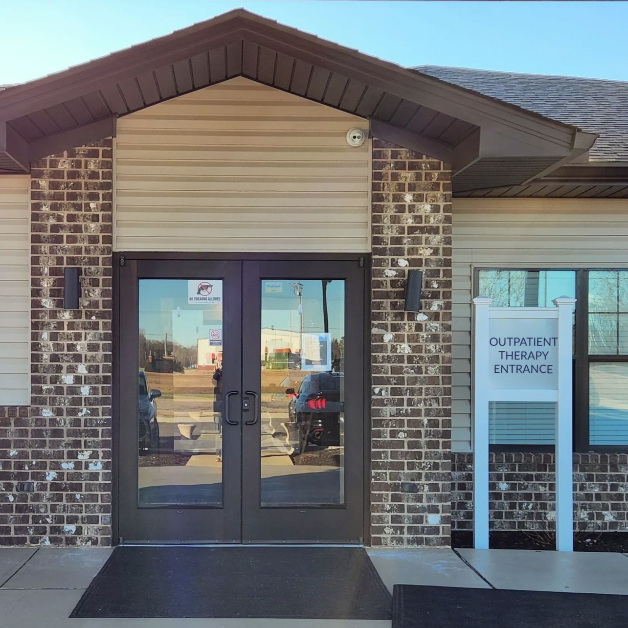 Entrance to a building with double glass doors, brick accents, and a sign that says