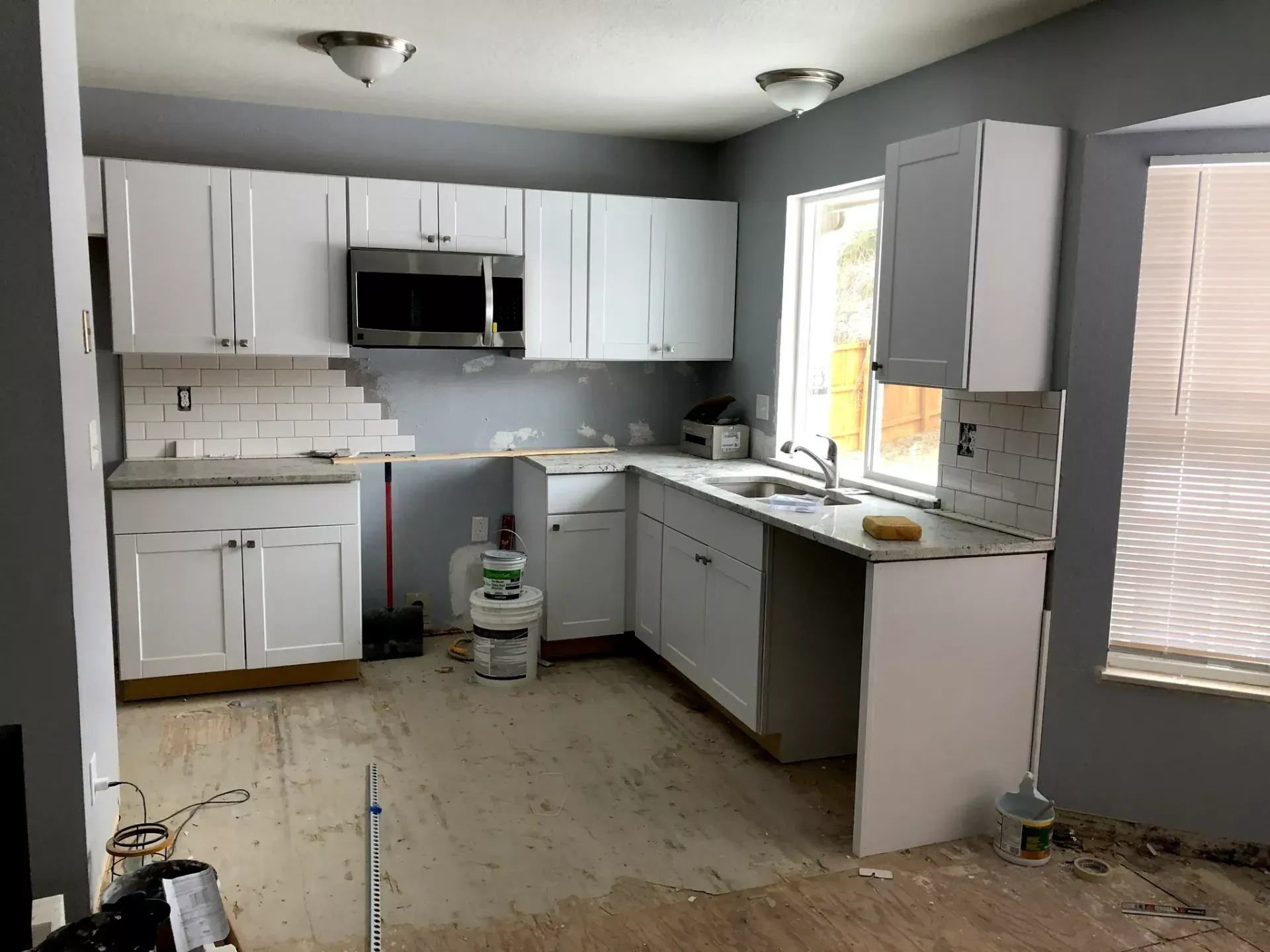 A kitchen with white cabinets, black countertops, and a window.