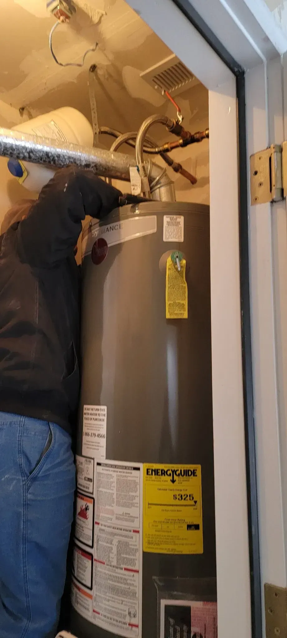 A person working on a hot water heater in a utility room.