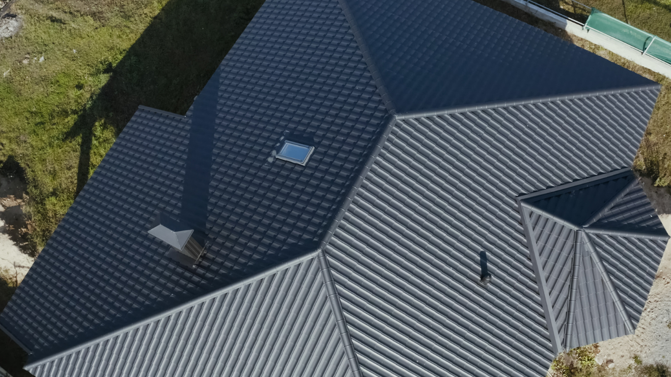 Dark gray metal roof on a house with multiple angles and a skylight, viewed from above.