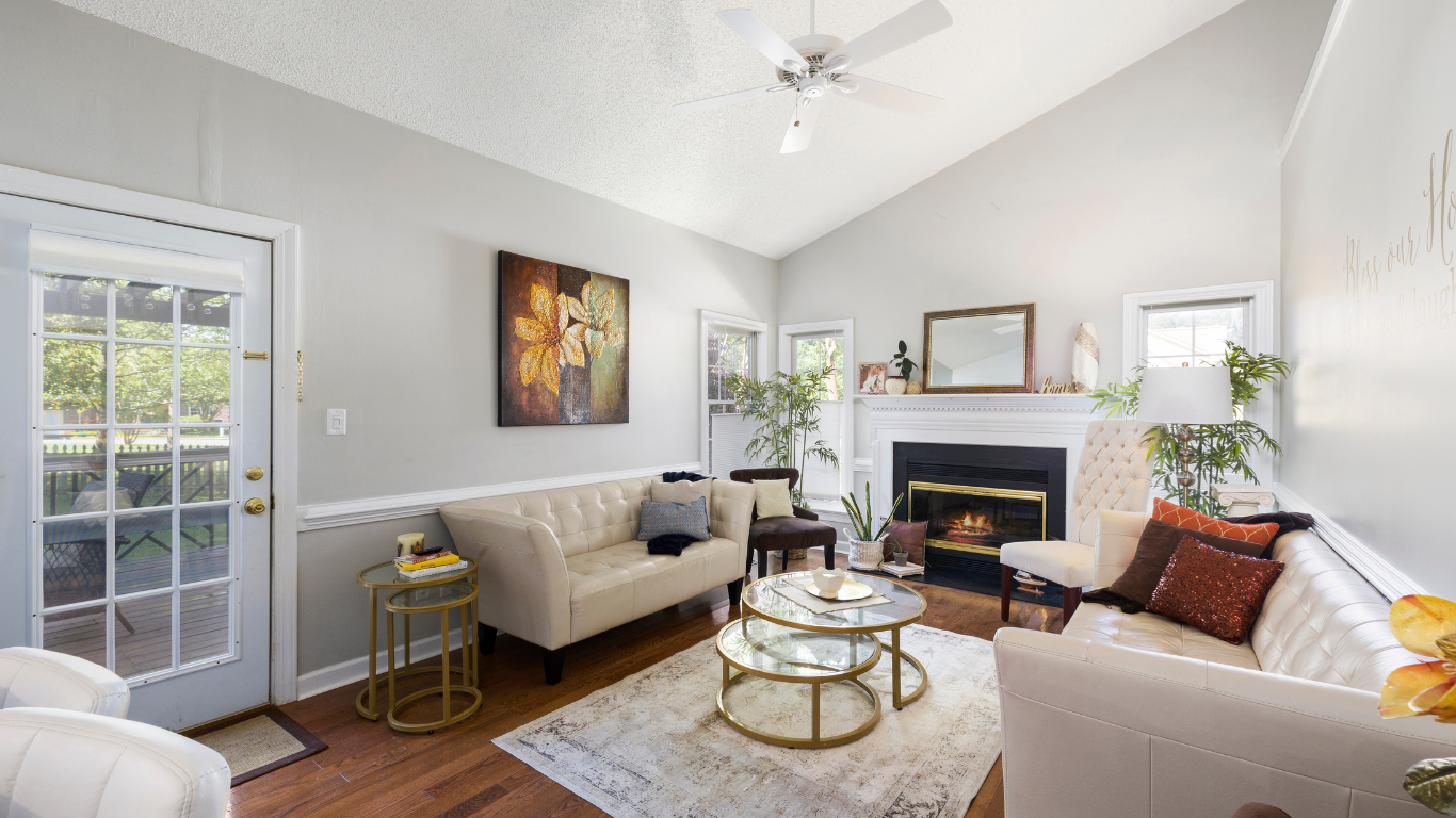 Living room with white couches, fireplace, and glass coffee tables.