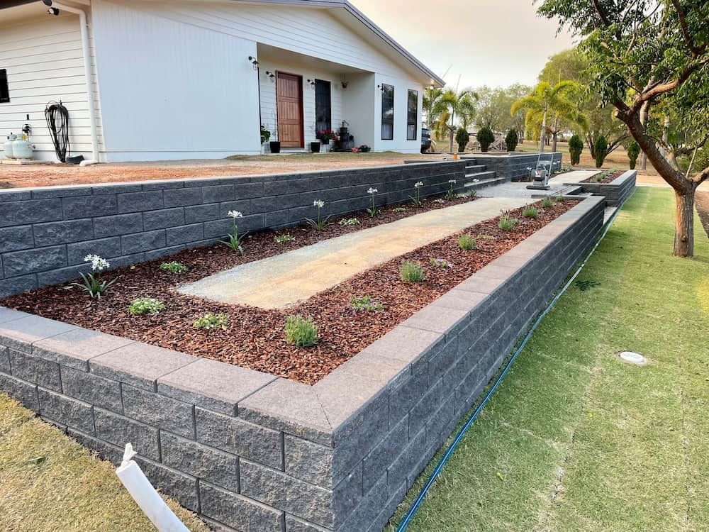 Raised Flower Beds With Dark Gray Block Retaining Walls in Front of a White House — LS Plant Hire in Calliope, QLD