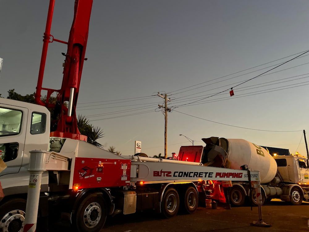 Concrete Pumping Truck at Dusk, Extending Boom Over a Concrete Mixer Truck — LS Plant Hire in Calliope, QLD