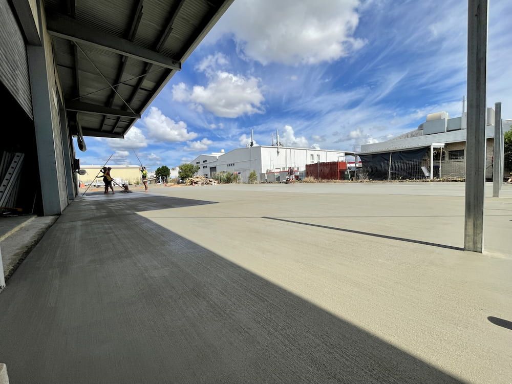 Construction Site With Workers Smoothing a Freshly Poured Concrete Slab Under a Blue Sky — LS Plant Hire in Calliope, QLD