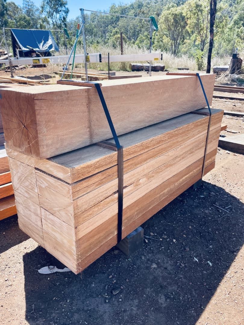 Stack of Light Brown Timber Boards, Bound With Black Straps, Outdoors in a Construction Site — LS Plant Hire in Calliope, QLD