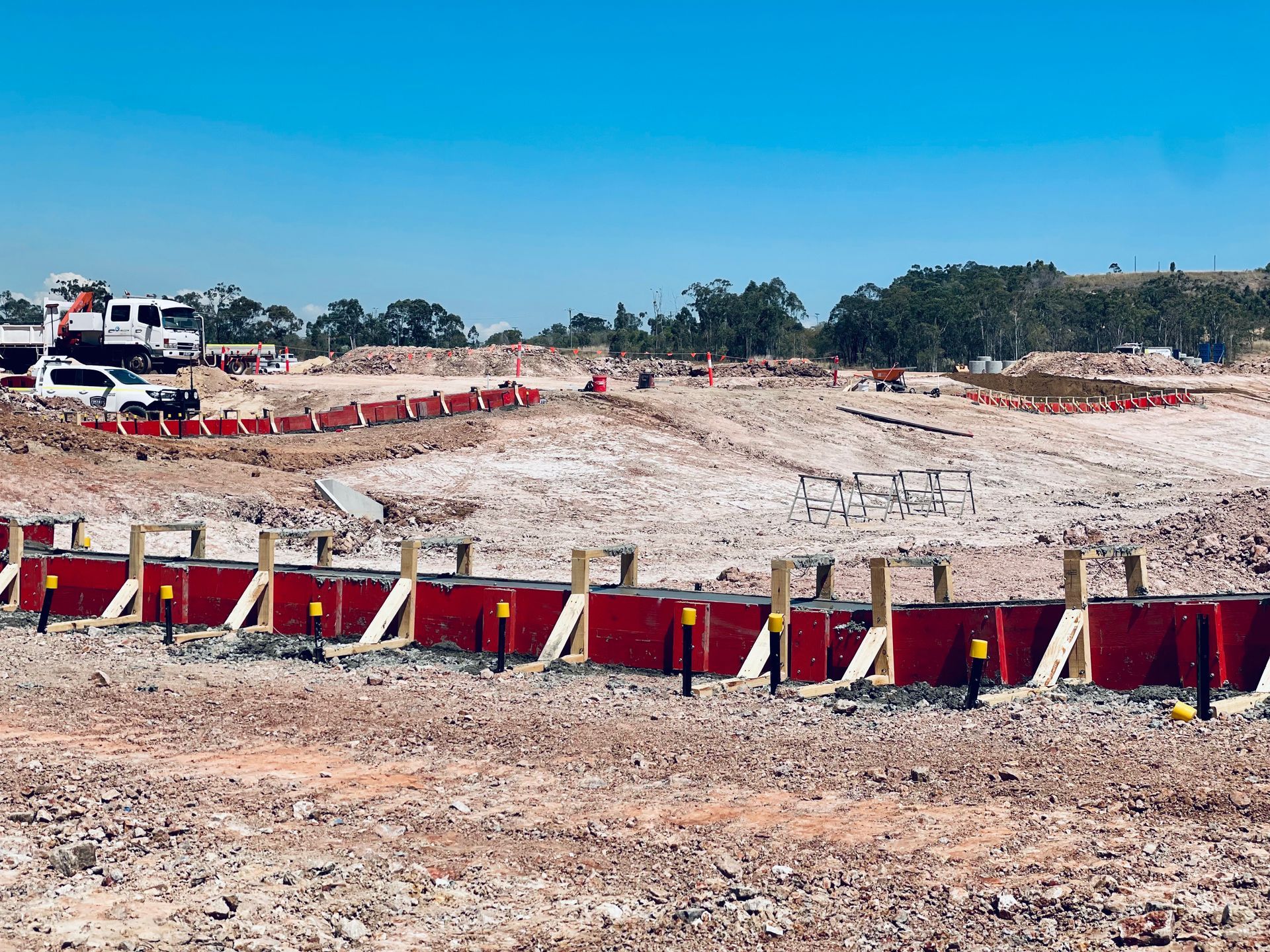 Construction site with red concrete forms lined up in the foreground against a clear blue sky. — LS Plant Hire in Calliope, QLD