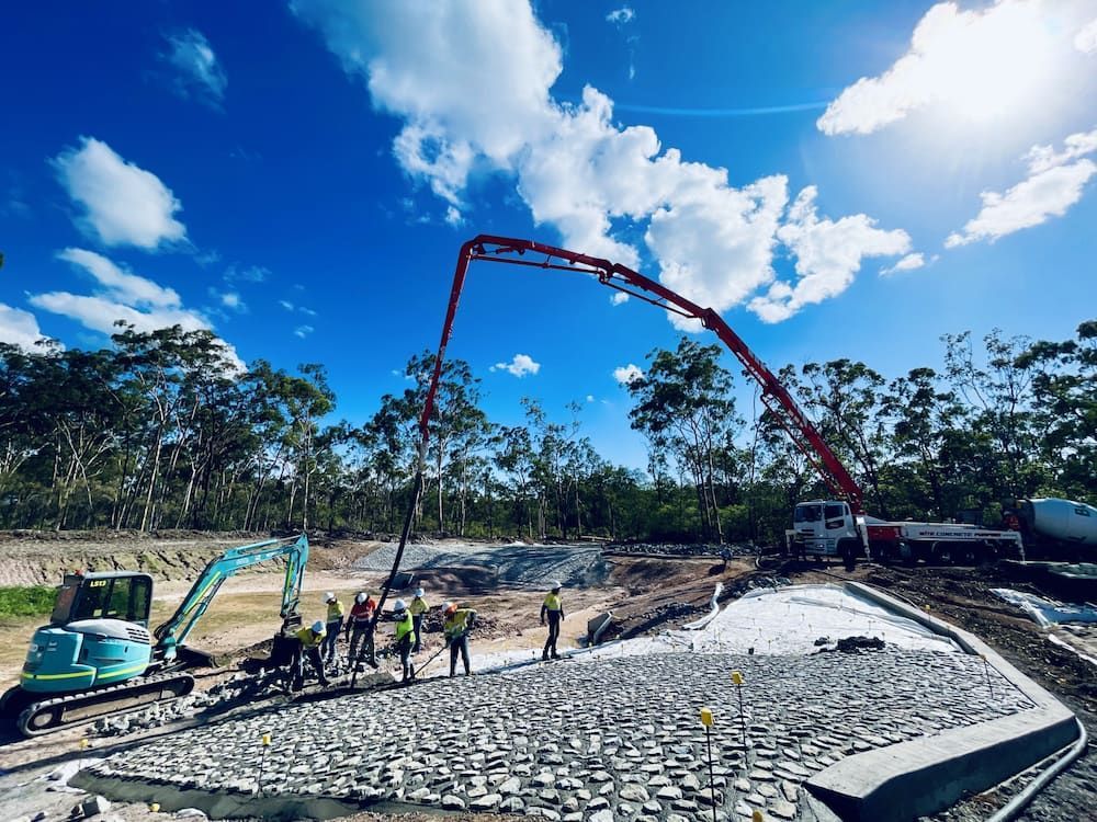 Construction Site: Concrete Pouring With Pump Truck, Excavator, Workers, Bright Blue Sky — LS Plant Hire in Calliope, QLD