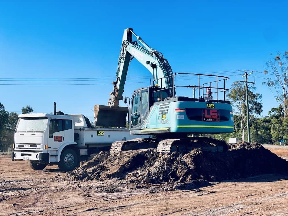 An Excavator Loading Dirt Onto a Truck in a Construction Setting. Sunny Day — LS Plant Hire in Calliope, QLD